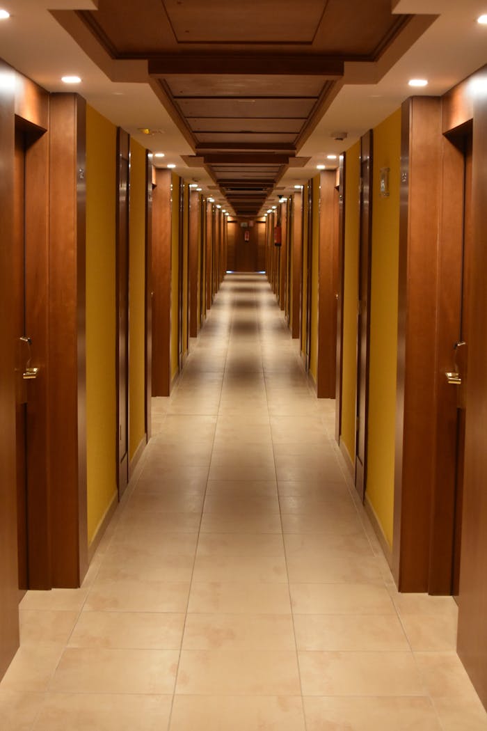 Home Long hallway view of a modern hotel with wooden doors and ceiling, creating a luxurious ambiance.